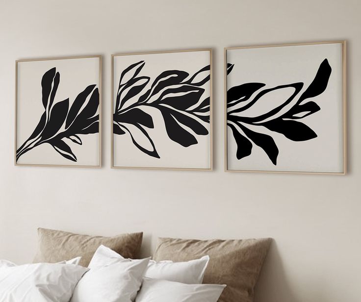 three black and white paintings on the wall above a bed