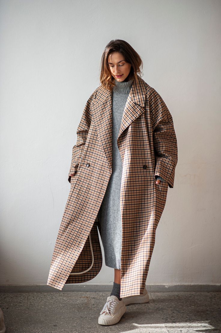 "This double-breasted raglan sleeve trench coat is a wardrobe staple that will elevate every look. Crafted from a quality cotton blend, this minimalist plaid coat is an absolute go-to when transitioning seasons. The oversized longline silhouette with broad lapels and spacious pockets easily matches different styles, be it your formal office attire or a laid-back everyday outfit. The raglan sleeves give you some more room for the shoulders, making this fit suitable for men too. This maxi coat comes without a lining, but every inner seam is carefully covered with binding to give them extra reinforcement and make the coat last longer. If you are looking for a piece that you can wear many seasons in the future, this is the one that you should add to your multi-purpose wardrobe.  WHY PATIS PROJ Checked Trench Coat Outfit, Long Over Coat Women, Check Trench Coat Outfit, Over Sized Trench Coat, Long Coat Outfit Summer, Womens Overcoat Outfits, Check Coats For Women, Long Coat Over Dress, Big Trench Coat Outfit