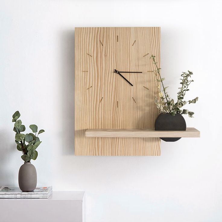 a wooden clock mounted to the side of a wall next to a potted plant