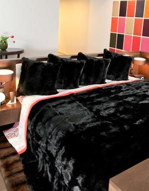 a bed with black comforter and pillows on it next to a night stand in a bedroom