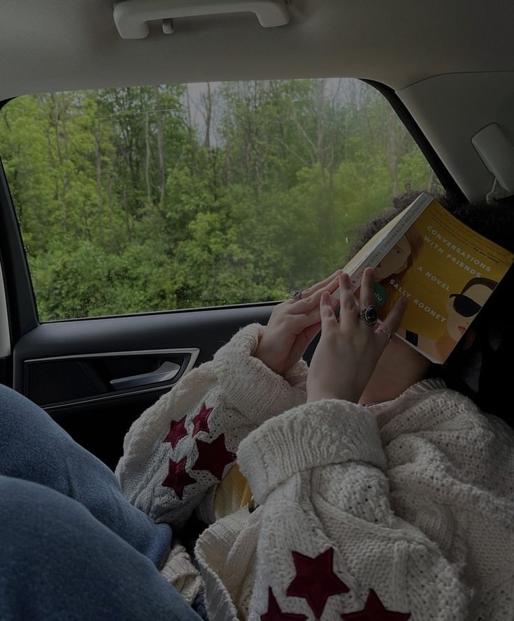 a person sitting in the back seat of a car reading a book