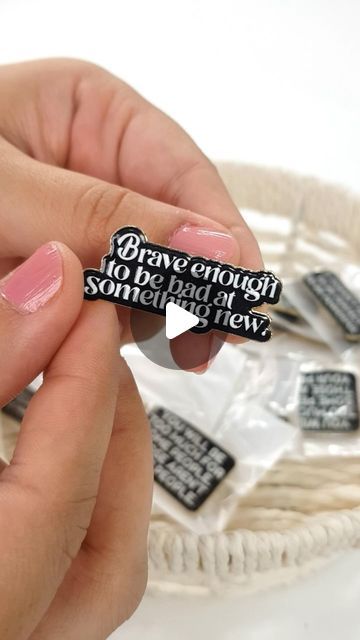 a person holding a small black and white sticker in their left hand with words on it