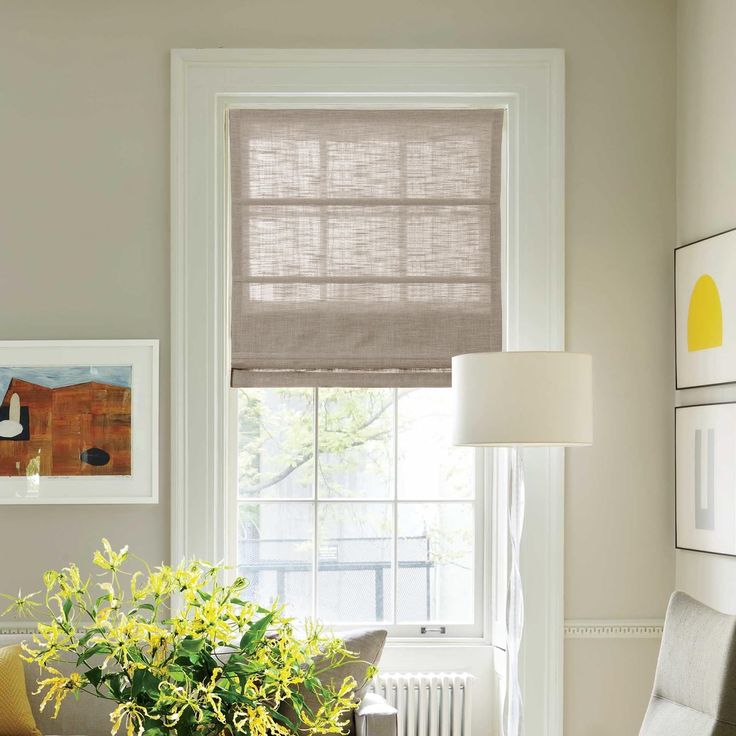 a living room filled with furniture and a window covered in roman blind shades on the windowsill