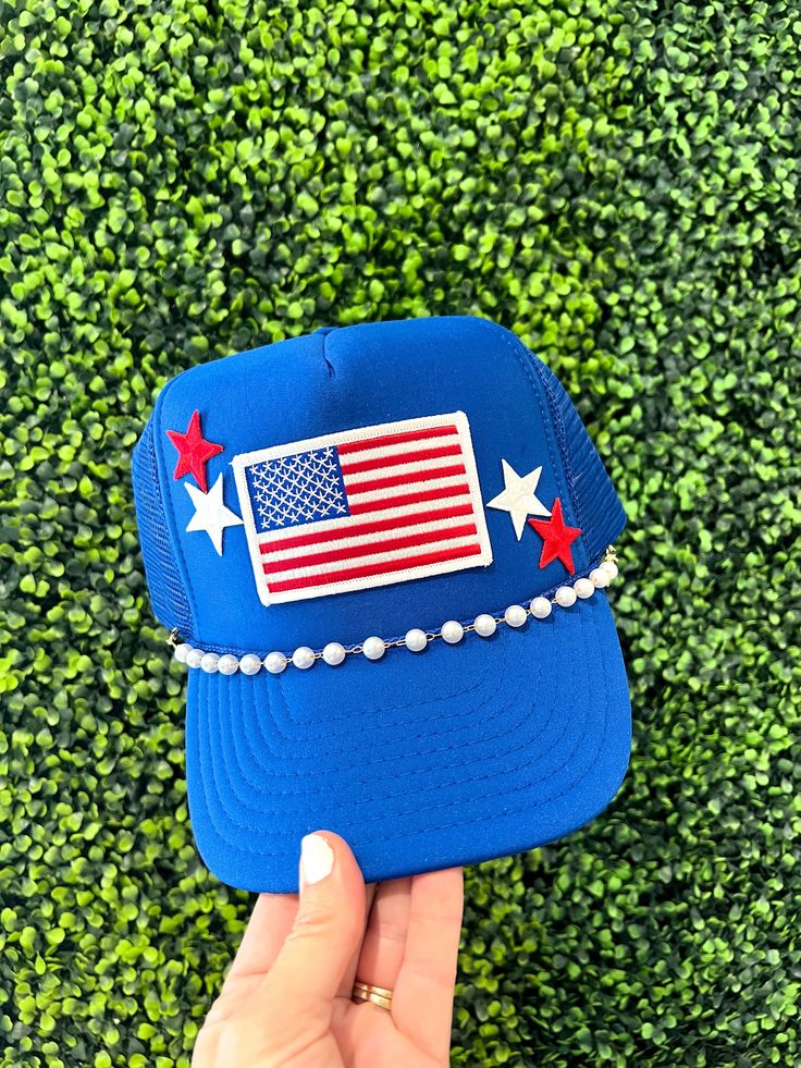 The perfect accessory for the summer and all the patriotic events!! Hat comes with flag  patch and star patches. Also features a hat chain.  Choose your color hat to fit your style. We have several color options to choose from. Hat Details: 100% Polyester foam front, mesh back Structured, five-panel, mid-profile 3 ½" crown Pre-curved visor with braid detailing Adjustable double snapback closure Summer Patriotic Trucker Hat With Curved Brim, Patriotic Adjustable Hat For Independence Day, Adjustable Americana Hat For 4th Of July, Adjustable Blue Trucker Hat For 4th Of July, Patriotic Adjustable Trucker Hat For 4th Of July, Patriotic Trucker Hat For 4th Of July, Patriotic Summer Snapback Trucker Hat, Blue Baseball Cap For 4th Of July, Adjustable Patriotic Hats