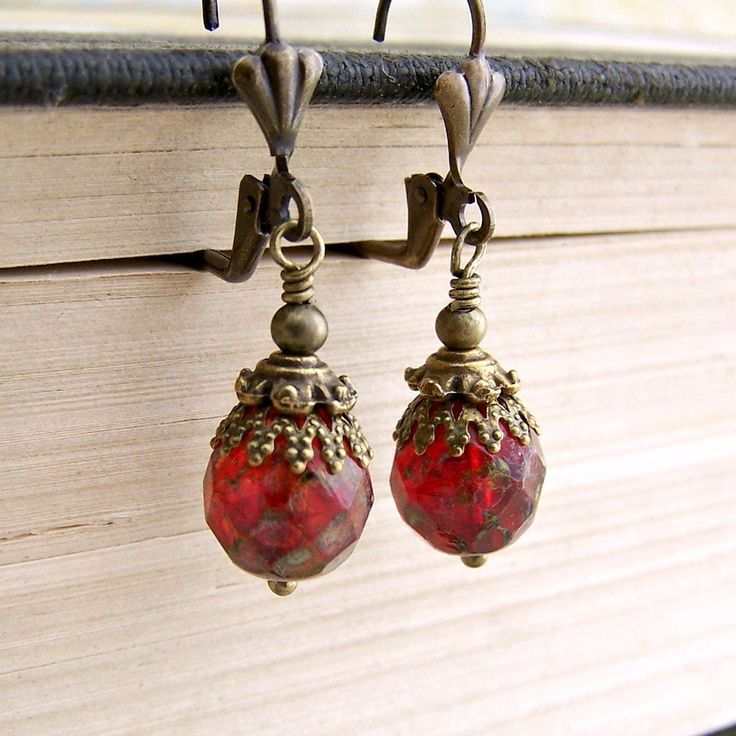 Get ready for a carnival in Venice with these red and brass earrings. The ornate brass caps mimic the charm and grandeur of Venice. The red faceted Czech glass beads have a Picasso finish that make the beads appear to have an aged patina. Depending on the light they can either glow a warm red or have a deeper matte red look.   From the top curve of the lever back ear wires to the bottom of the ball tipped head pin these earrings measure 1 1/2 inches (3.7 cm) long. Other ear wire styles are avail Cheap Red Czech Glass Earrings, Ornate Red Dangle Earrings, Ornate Red Earrings For Party, Gift Brass Beaded Earrings With Round Beads, Ornate Red Teardrop Jewelry, Vintage Czech Glass Beaded Earrings As Gift, Red Faceted Beads Earrings For Festive Occasions, Vintage Red Faceted Beads Jewelry, Vintage Brass Beaded Earrings For Pierced Ears