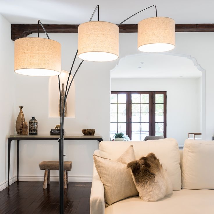 a living room with white couches and two lamps on the wall above them in front of a table