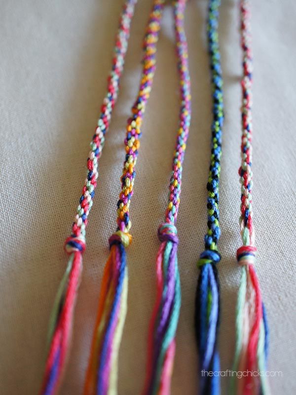 multicolored necklaces are hanging on a white tablecloth, with one bead in the middle