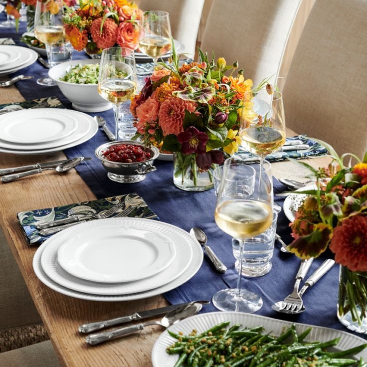 a table set with plates, silverware and vases filled with flowers on it