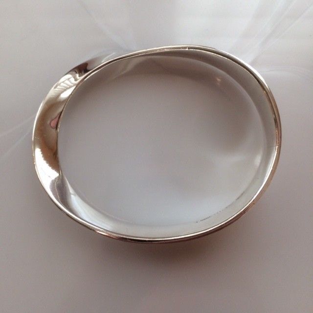 "We are pleased to offer a lovely Georg Jensen Sterling Silver Modernist bangle that was designed by Vivianna Torun in 1960's. The design is known as \"Mobius\". We believe that it will fit almost all wrists. It is a slight oval and measures approx. 2 5/8 inches (68mm) by 2 3/8inches (59mm), and weighs approx. 63 grams. As the photos demonstrate, the bangle is in auperb condition.  There are no dings scratches or other flaws.  So that you may buy with confidence, we offer a full fourteen day cas Polished Hoop Bangle As A Gift, Formal Bangle Bracelet With A Modern Twist, Formal Bangle With Modern Twist, Modern Polished Sterling Silver Bangle, Modern Polished Sterling Silver Bangle Bracelet, Modern Shiny Round Cuff Bracelet, Modern Sterling Silver Bangle With Polished Finish, Modern Round Cuff Bracelet With Shiny Finish, Modernist Silver Bangle With Polished Finish