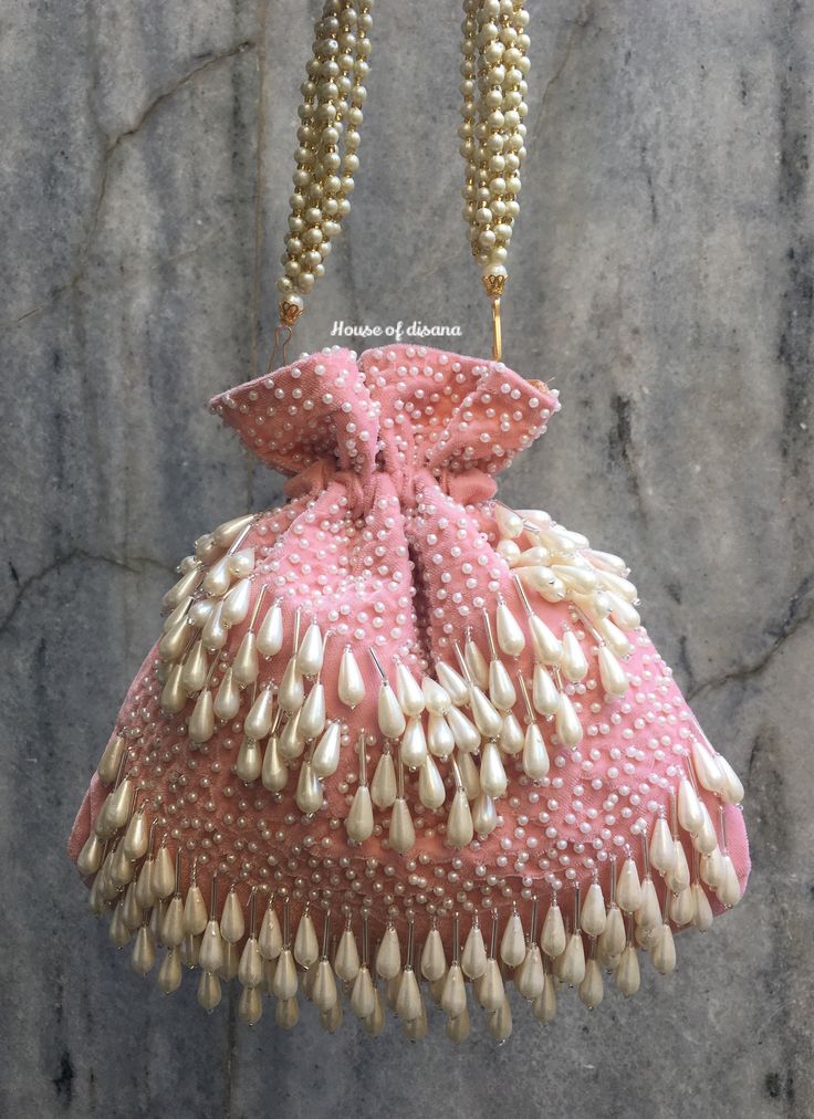 This is a beautiful handcrafted potli bag made with love.It has intricate handwork which showcases the Indian craftsmanship by our local artisans. It comes with a matching pearl handle. Details  - Both side handwork  - Fabric lining on the inside to keep your belongings safe  - Drawstring lock closure  - Detachable handle This clutch can be worn as a crossbody bag or a shoulder bag with the sling chain or can simply be carried in hand.It is spacious enough to carry mobile phones, lipsticks, Keys Elegant Pink Shoulder Bag For Festive Occasions, Elegant Festive Potli Bag With Dori Work, Handwork Potli Bag For Wedding Diwali, Elegant Pink Shoulder Bag For Festivals, Wedding Handwork Potli Bag For Diwali, Elegant Potli Bag With Dori Work For Celebrations, Wedding Potli Bag With Handwork For Diwali, Clutch Potli Bag With Dori Work For Gift, Gift Pouch Clutch With Dori Work