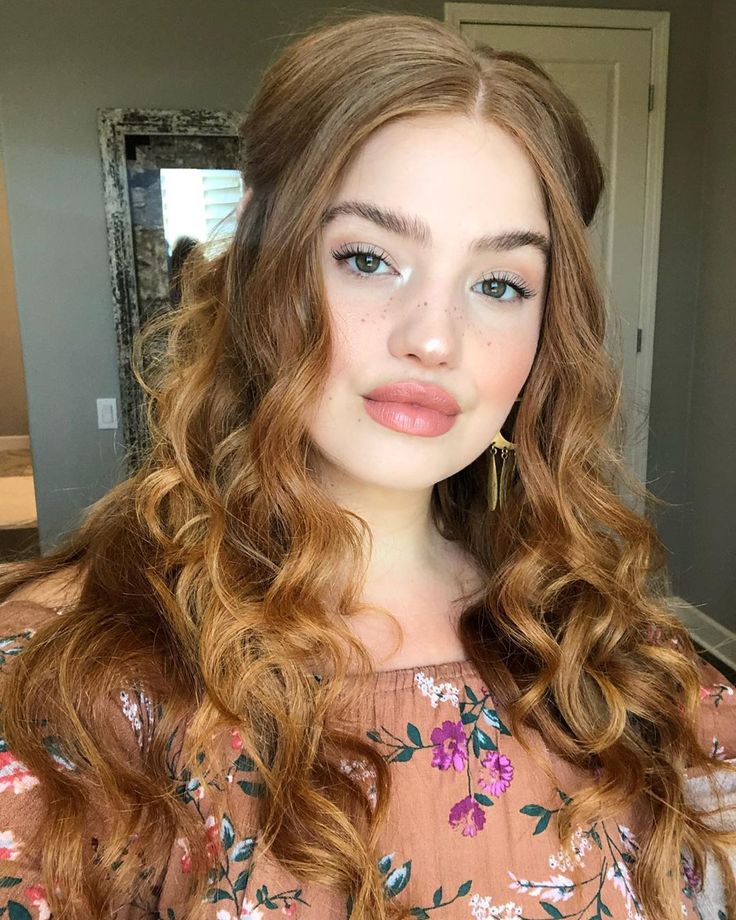 a young woman with long, curly hair is posing for the camera