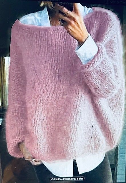 a woman wearing a pink sweater is taking a selfie