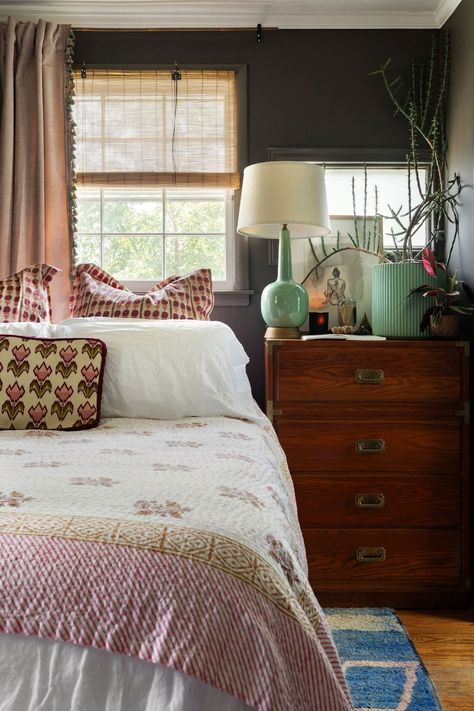 a bed sitting in a bedroom next to a window with curtains on top of it