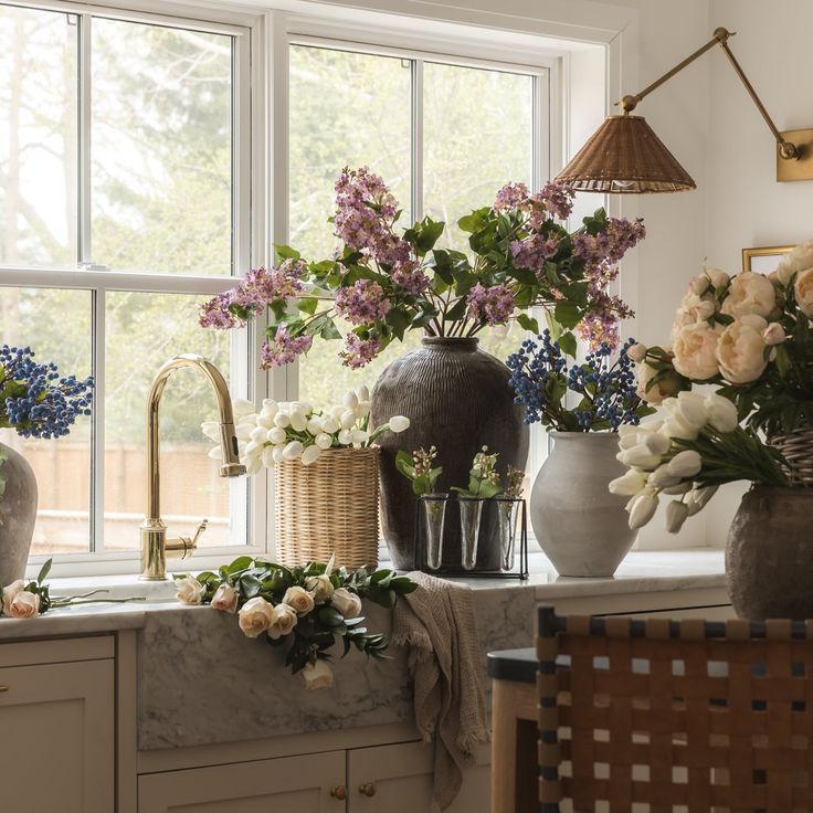 flowers are in vases on the kitchen counter next to the sink and window sill