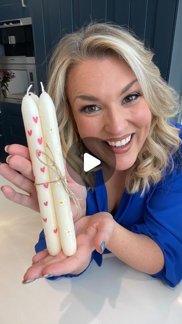 a woman is holding two candles in her hands and smiling at the camera, with hearts on them