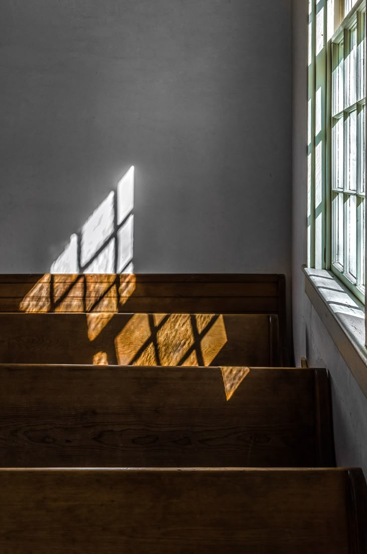 sunlight shining through the windows onto some wooden steps in a church with stained glass windows