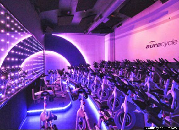 an indoor gym with rows of stationary exercise bikes and lights on the wall behind them