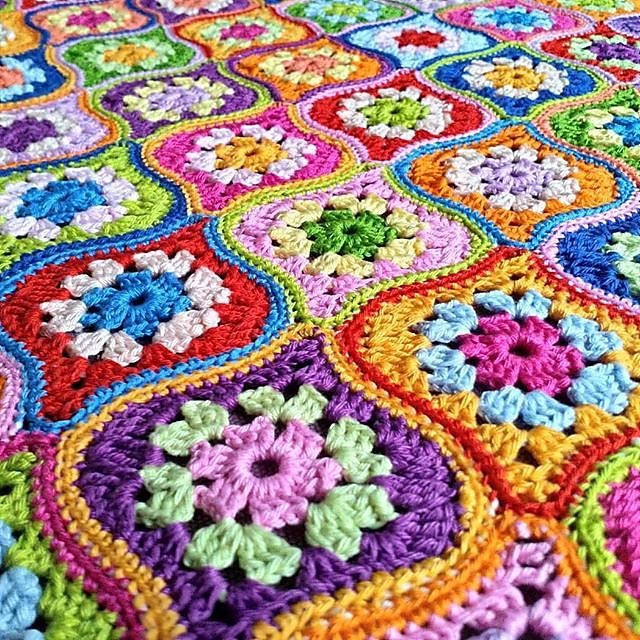 a colorful crocheted blanket is laying on the floor