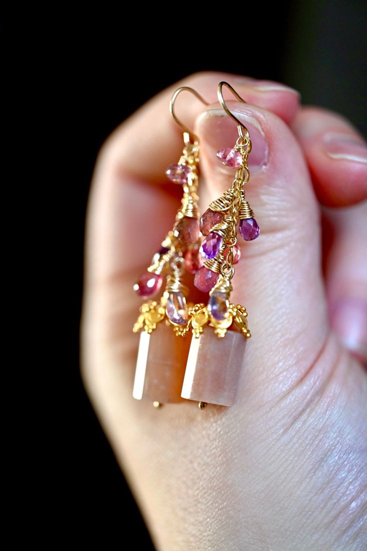 Gorgeous Sparkling Orchid Earrings. These feature pink and purple hued sapphires with an amethyst dangling between them and a small pink tourmaline atop. The gorgeous cylinder peach moonstone has a glittery flash that glitters in the light. There are 14K gold vermeil (over sterling) bead toppers on the moonstone. 14K gold filled (over sterling) beads, chain and hoops. 2 3/8” Length Kyanite Earrings, Orchid Earrings, The Orchid, Larimar Pendant, Beads Chain, Peach Moonstone, Earrings Studs, Opal Earrings, Labradorite Pendant