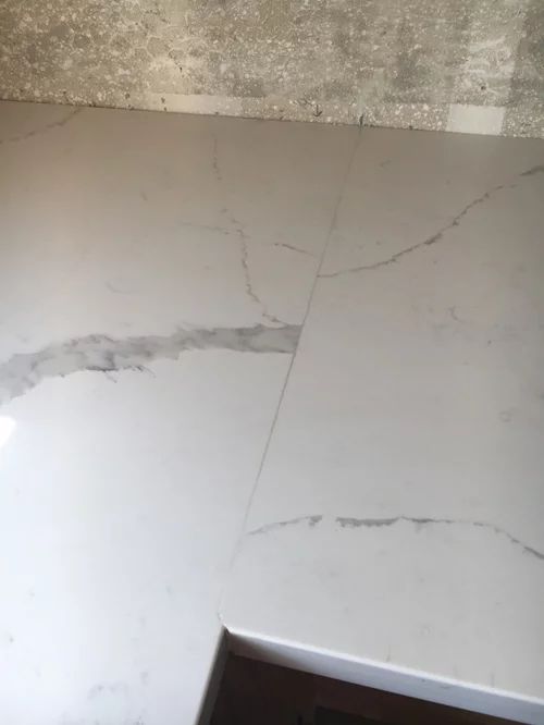 a white marble counter top with cracks in the middle and an open door leading to another room