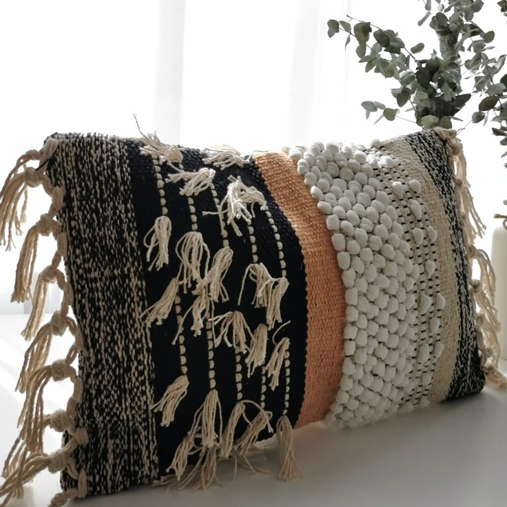 a black and white pillow sitting on top of a table next to a potted plant