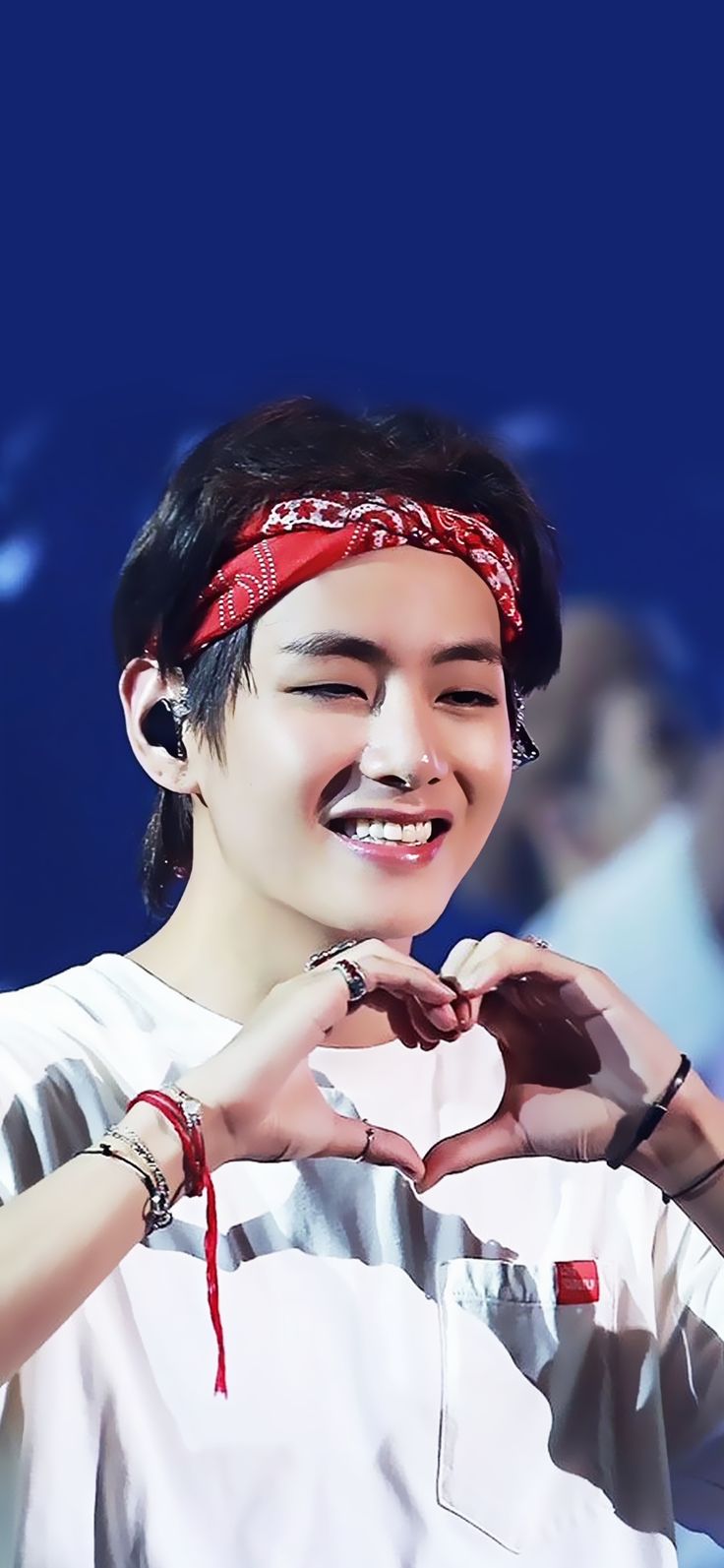 a young man making a heart shape with his hands while wearing a bandanna around his head