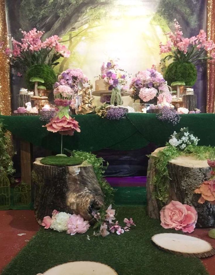 the table is decorated with pink flowers and greenery, along with two stumps