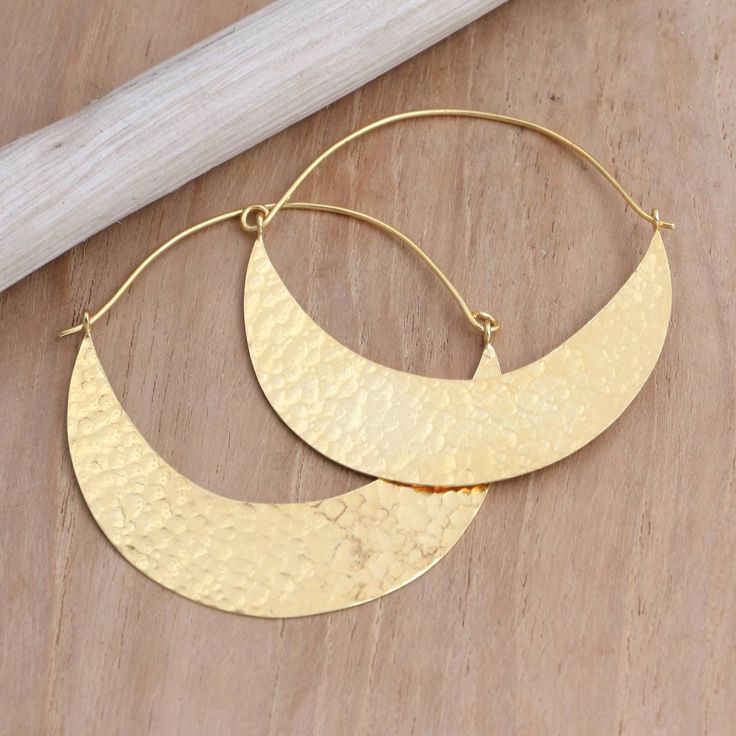 Glamorous and sophisticated, Wayan Karang's hoop earrings are carefully designed with semi-circles of shimmering gold resembling a canoe. Balinese artisans use 22k gold-plated brass to hand craft the earrings, treating the precious metal with a unique hammered finish. Handmade Semi-circle Gold Jewelry, Elegant Gold Half Moon Hoop Earrings, Elegant Half Moon Gold Hoop Earrings, Gold Semi-circle Brass Jewelry, Modern Gold Crescent Hoop Earrings, Metal Semi-circle Hoop Earrings For Pierced Ears, Semi-circle Metal Hoop Earrings For Pierced Ears, Metal Semi-circle Hoop Earrings, Gold Crescent Hammered Earrings