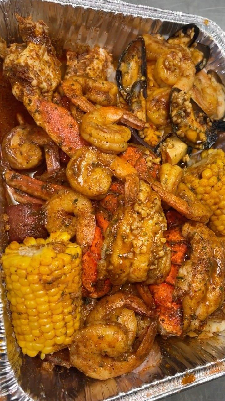 a tray filled with cooked shrimp and corn on the cob