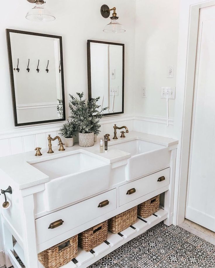 two sinks in a bathroom with mirrors above them and baskets under the sinks on either side