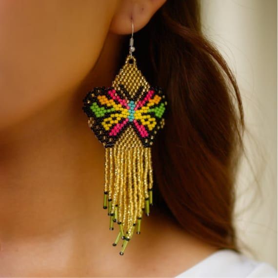 a close up of a woman's ear wearing earrings with beaded designs on it