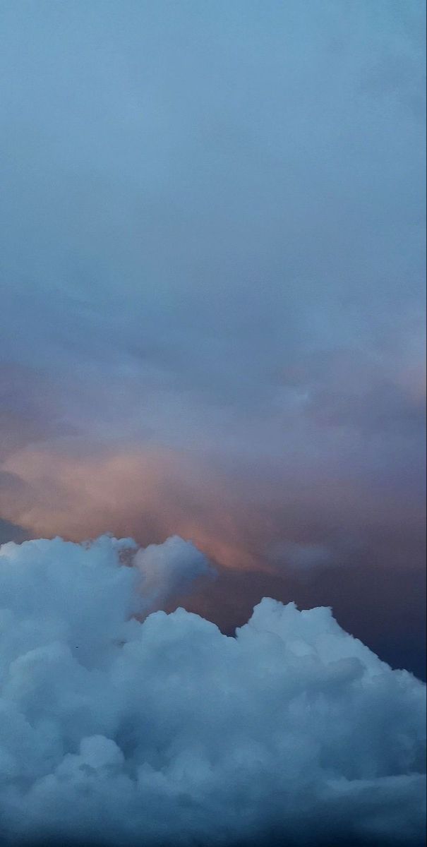 an airplane is flying high in the sky above some clouds at sunset or sunrise time