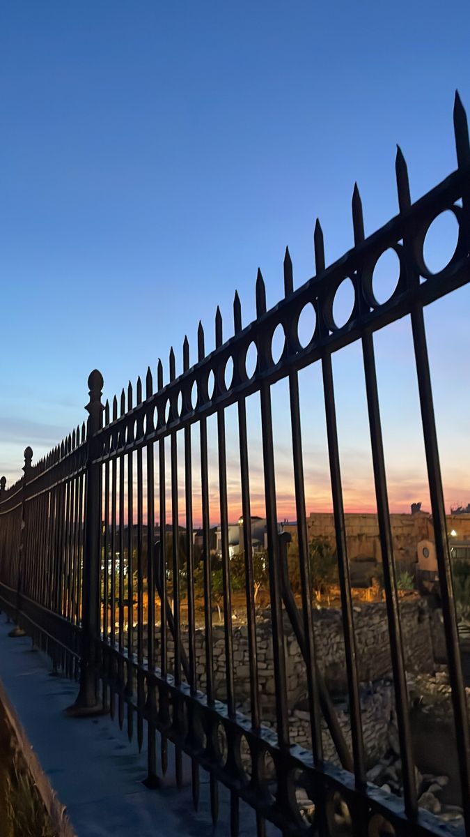 a black iron fence is shown against the blue sky