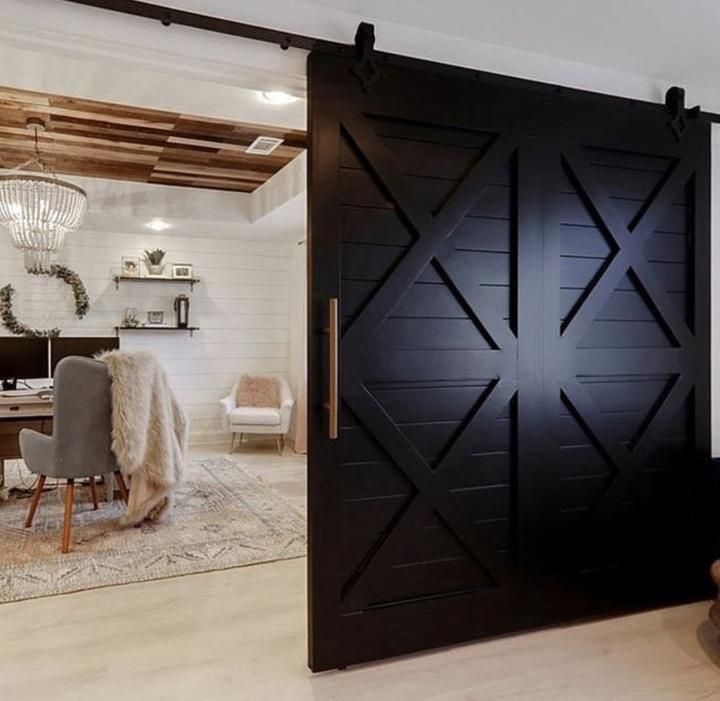 a living room filled with furniture next to a wooden door that has an x design on it