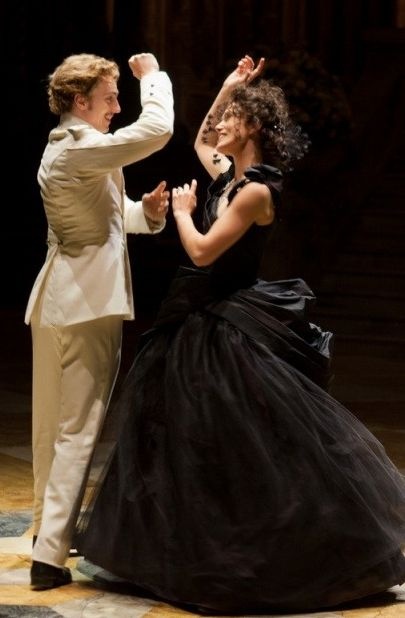 a man and woman in formal wear dancing on stage with their arms around each other