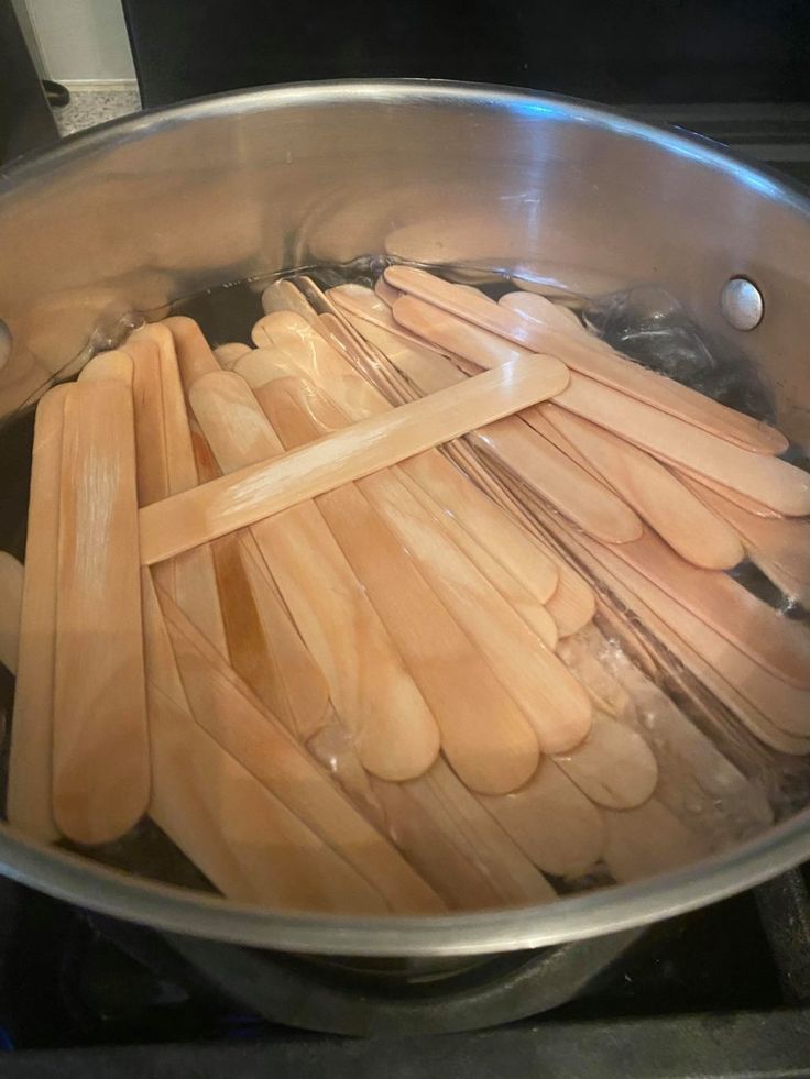 wooden utensils are being cooked in a pot on the stove top with water