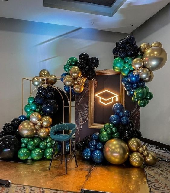 balloons are arranged in the shape of an arch on top of a table with a chair