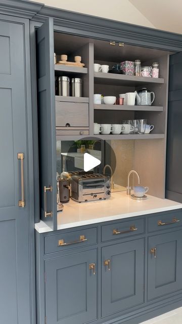 a kitchen with gray cabinets and white counter tops, gold pulls on the doors that open