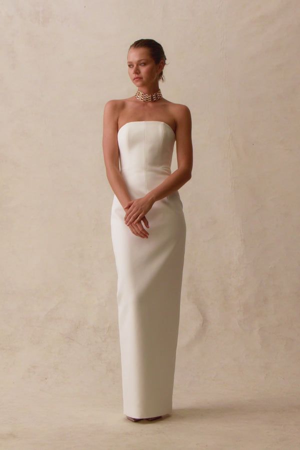 a woman in a strapless white dress poses for the camera with her hands on her hips