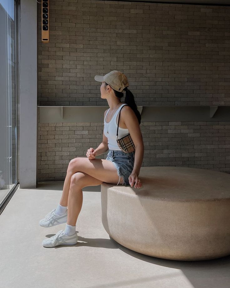 a woman sitting on top of a stone bench next to a brick wall and window