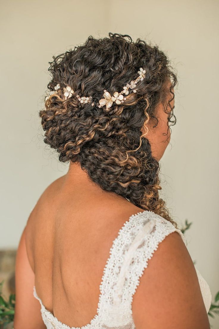 the back of a woman's head with curly hair and flowers in her hair