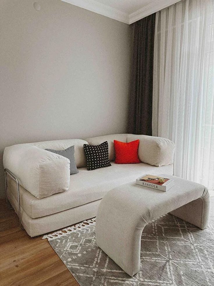 a living room with a white couch and ottoman