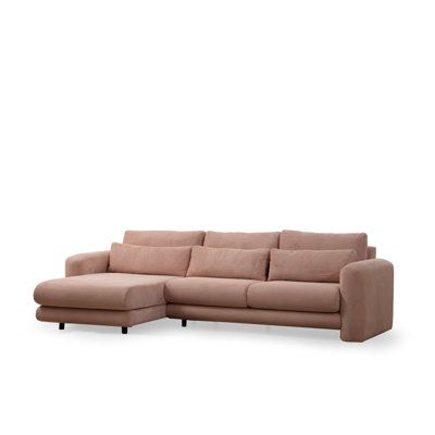 a beige sectional sofa with pillows on the top and bottom, in front of a white background