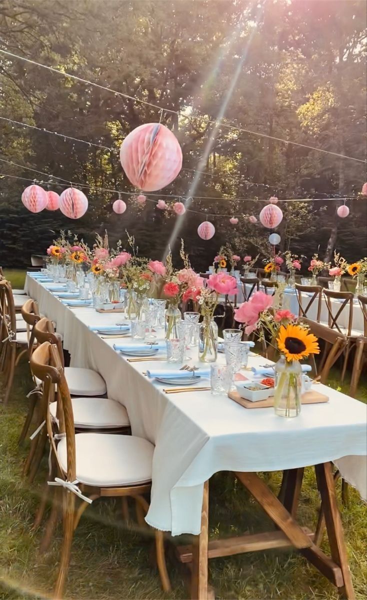 a long table is set up with paper lanterns and sunflowers in vases