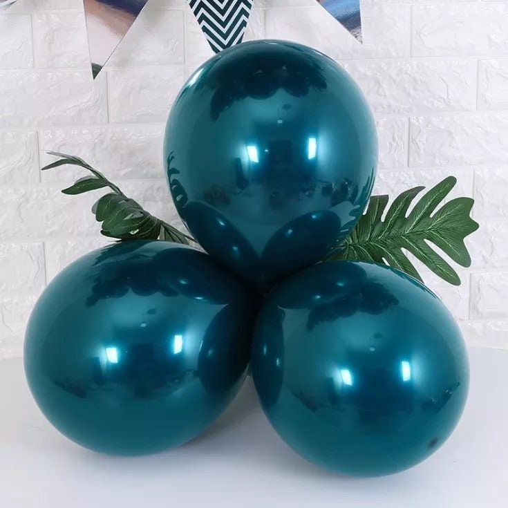 three shiny blue balloons sitting on top of each other in front of a white brick wall