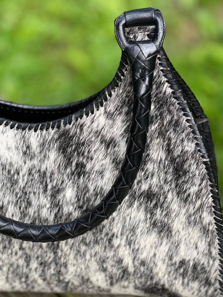 Handcrafted Shoulder - Hobo Bag "LUNA PELO" by ALLE is made of calf hair with a beautiful natural design in tones of Black & White hair, combined with black hand-tooled leather on the back and sides of the bag, it also has two hand-braided handles and hand-stitching adorning around the bag. Features a spacious interior with one zip-side pocket and two slip pockets on the other side. Perfect for everyday life! Calf Hair Body: hand-tooled Leather 15"W X 12"H X 4 1/2"D Handle Drop: 9" Two Tassels o Artisan Black Bag With Leather Handles, Black Hand Tooled Tote Bag, Artisan Black Bags With Leather Handles, Black Hand Tooled Bags For Everyday Use, Black Calf Hair Shoulder Bag For Everyday Use, Black Hand Tooled Tote Shoulder Bag, Black Hand Tooled Shoulder Bag For Everyday, Artisan Black Satchel Shoulder Bag, Black Calf Hair Bag With Leather Handles