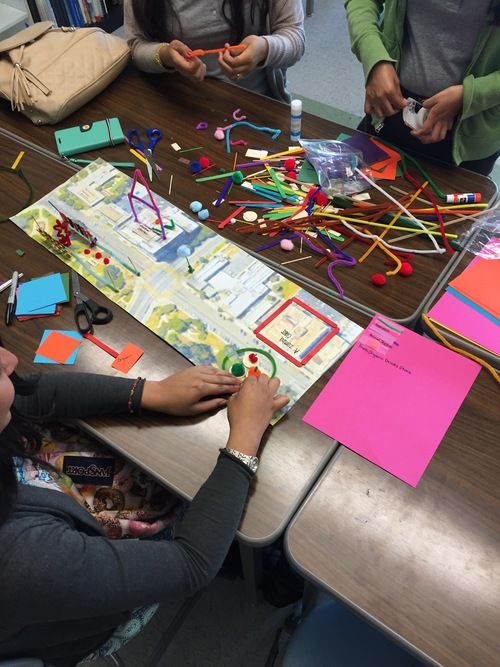 three women sitting at a table working on a project with colored paper and magnets