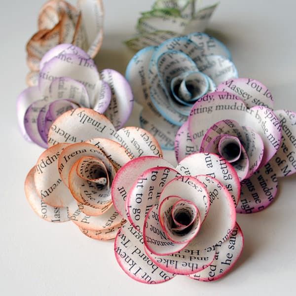 several rolled up paper flowers sitting on top of a white tablecloth covered surface with words written all over them