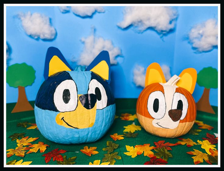 two pumpkins decorated to look like cartoon characters are sitting in front of a blue background