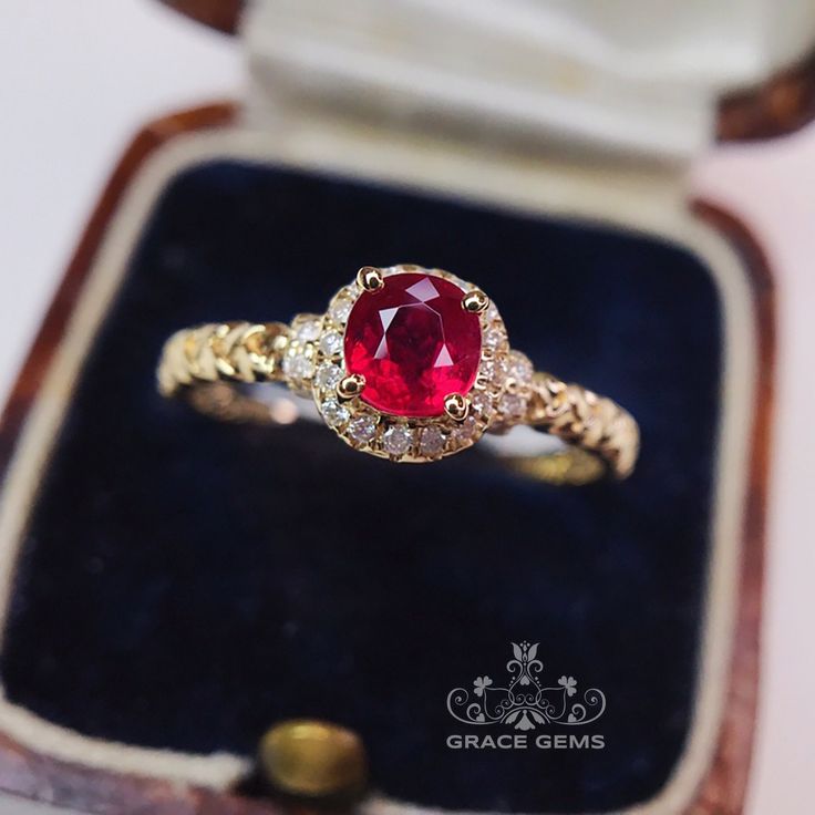 a ring with a red stone surrounded by white and yellow diamonds in a wooden box